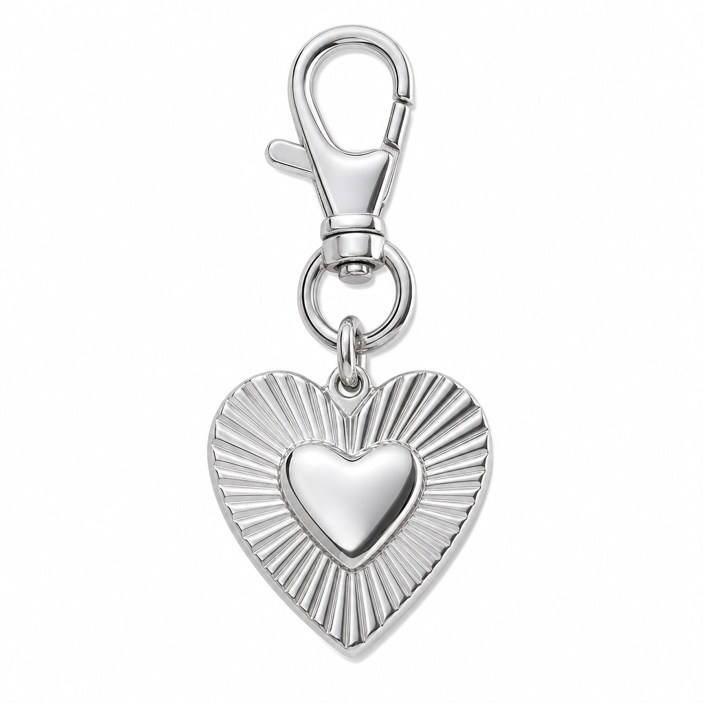 Premium boutique packaging scene with a stainless steel bag charm on a clean, neutral background