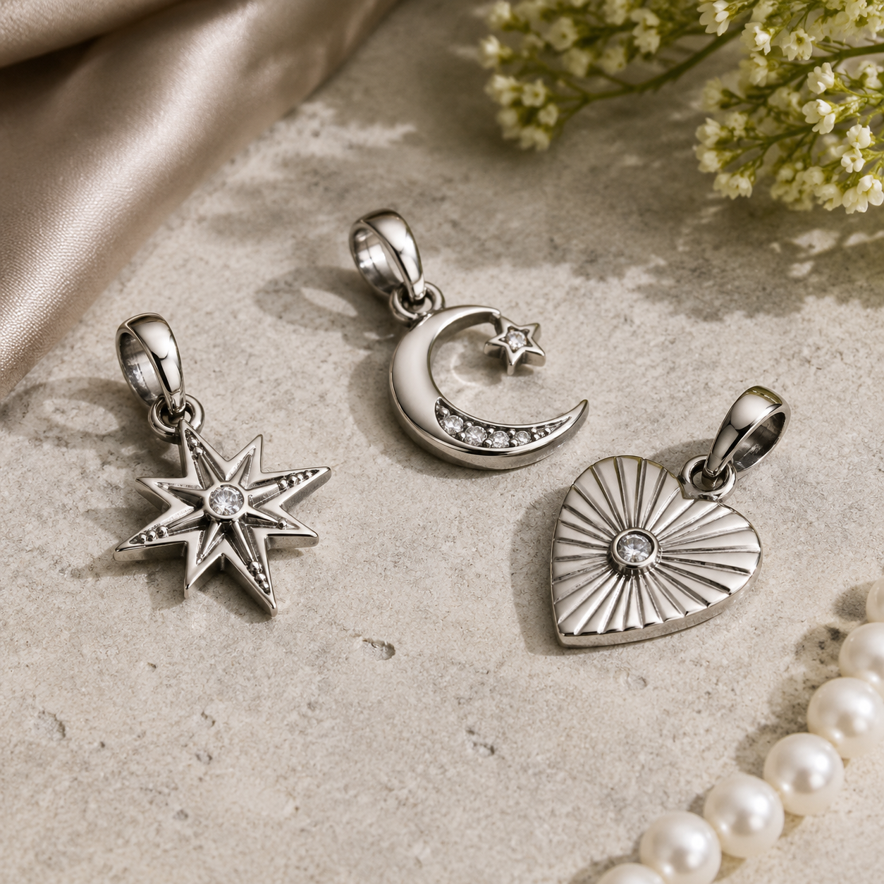 Studio product photography of customized 316L stainless steel charms with visible jump rings and premium packaging card