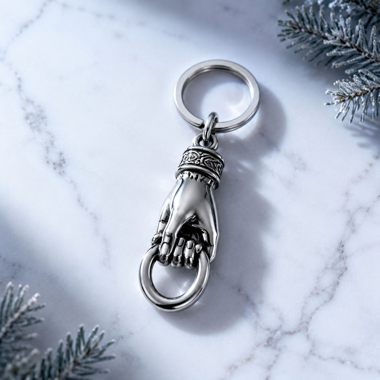 Studio product photography of a single 316L stainless steel hand holding keychain charm on a pure white background with visible jump ring attachment and realistic polished finish