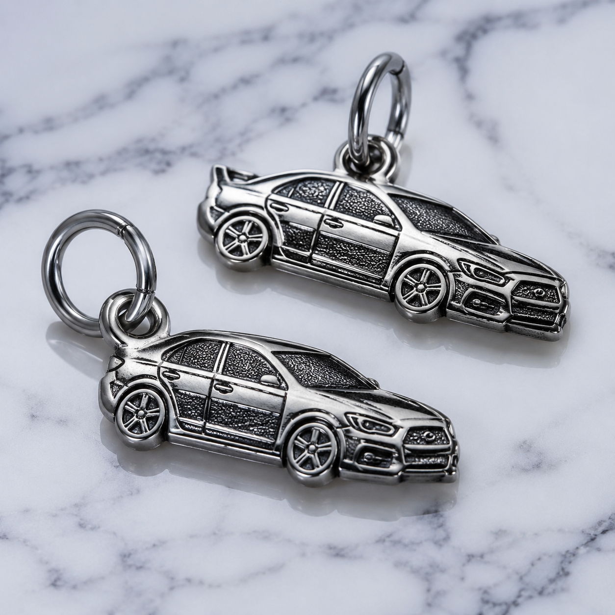 studio product photography of a single 316L stainless steel car charm with visible jump ring on a white background