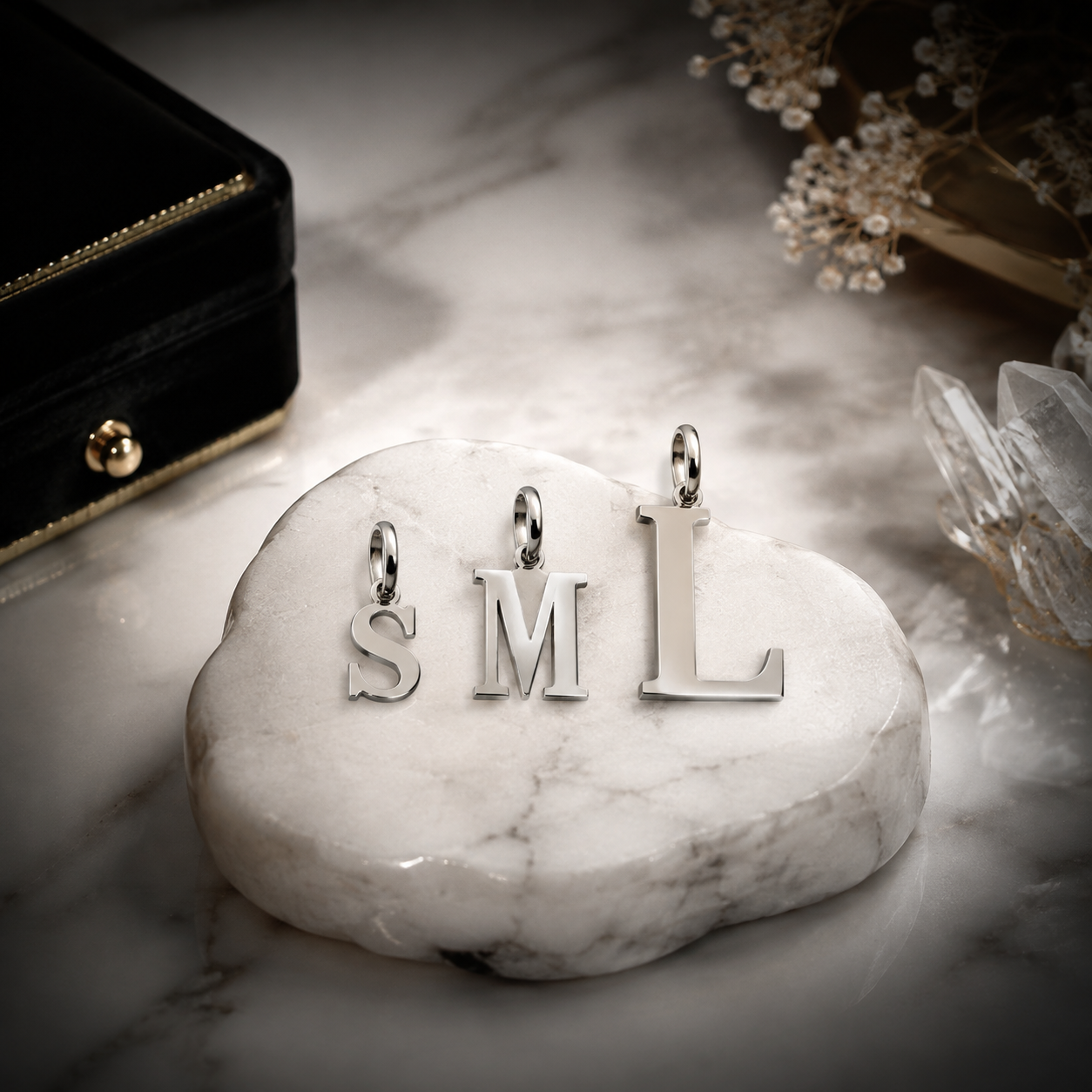 Studio product photography of organized 316L stainless steel letter charms on a neutral display tray