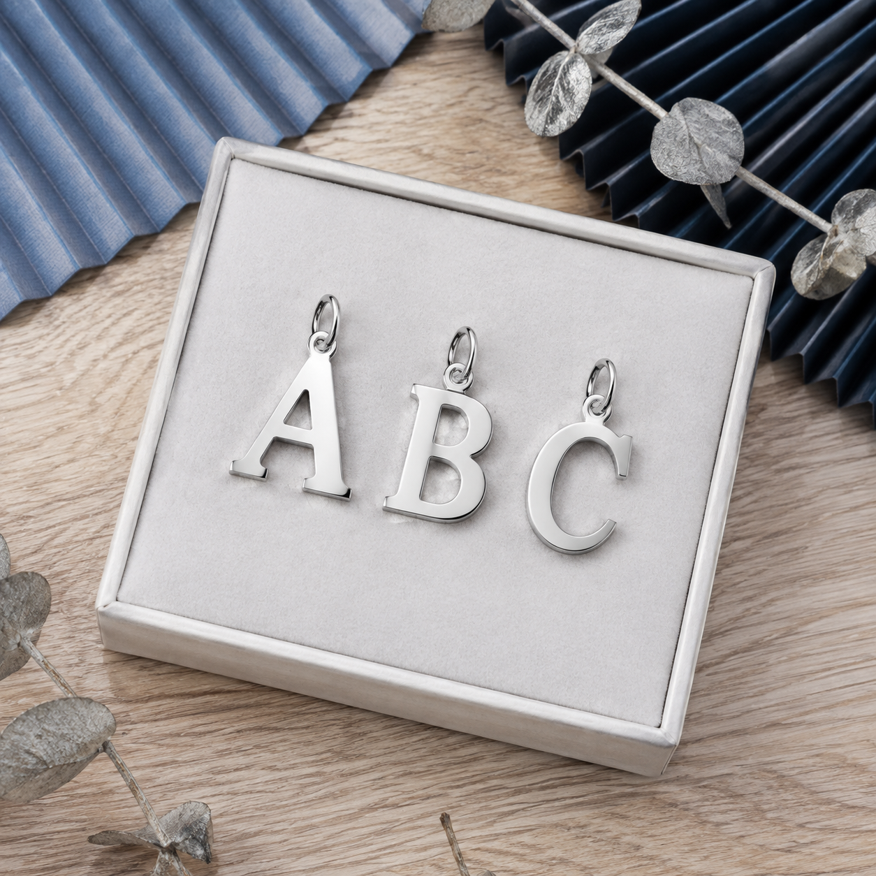 studio product photography of customized 316L stainless steel letter charms on a clean white background